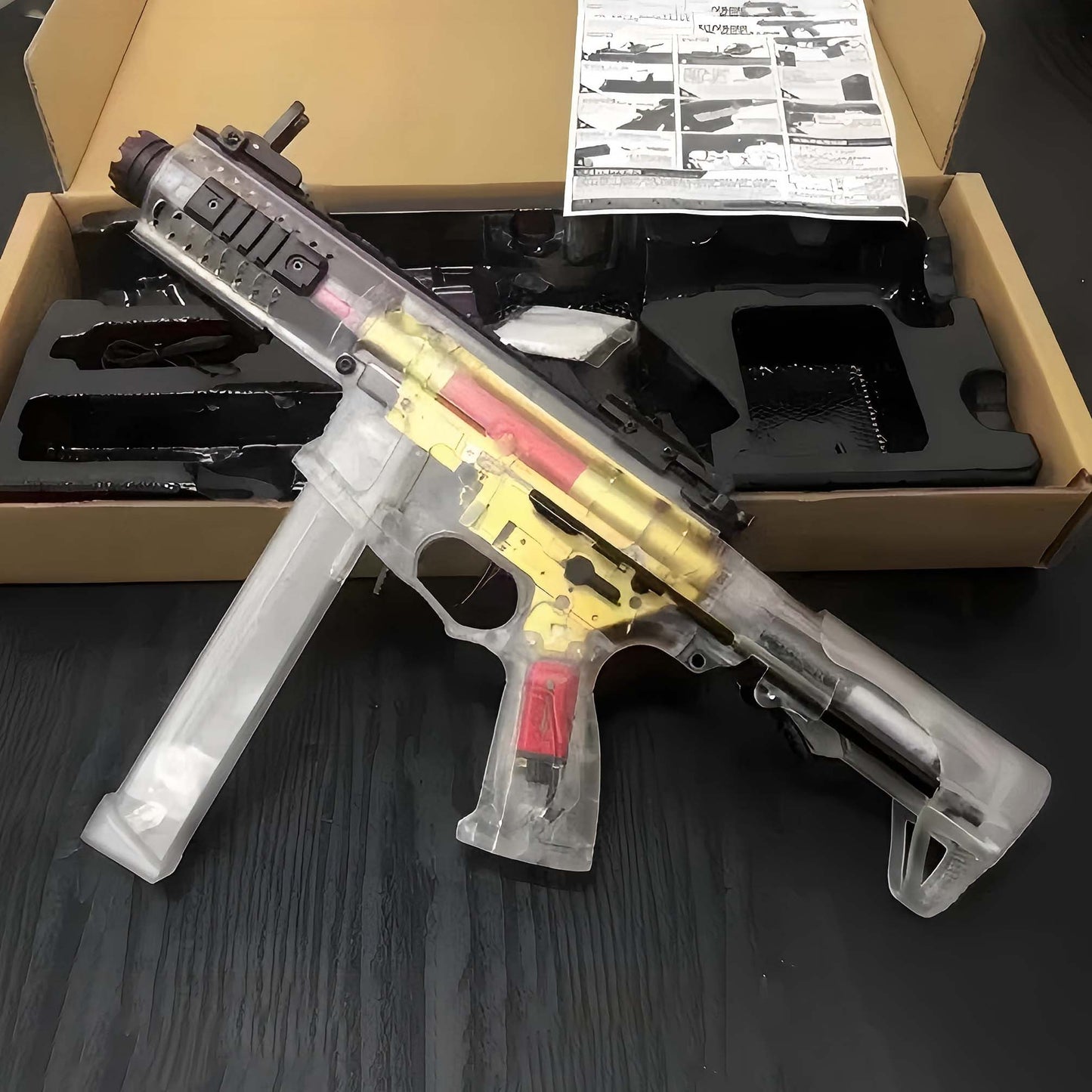 ARP9 Gel Blaster Transparent Body + Golden Gearbox on a dark surface, with packaging in the background.